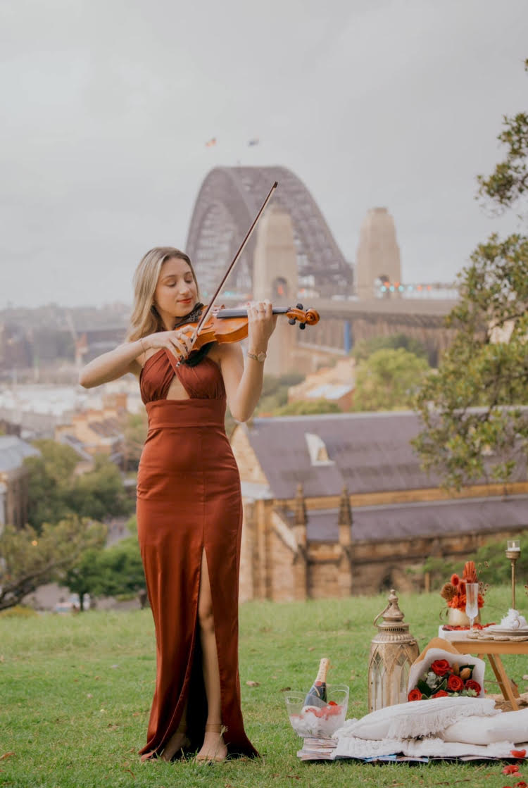 Tali playing violin at park in front of the Sydney Harbour Bridge